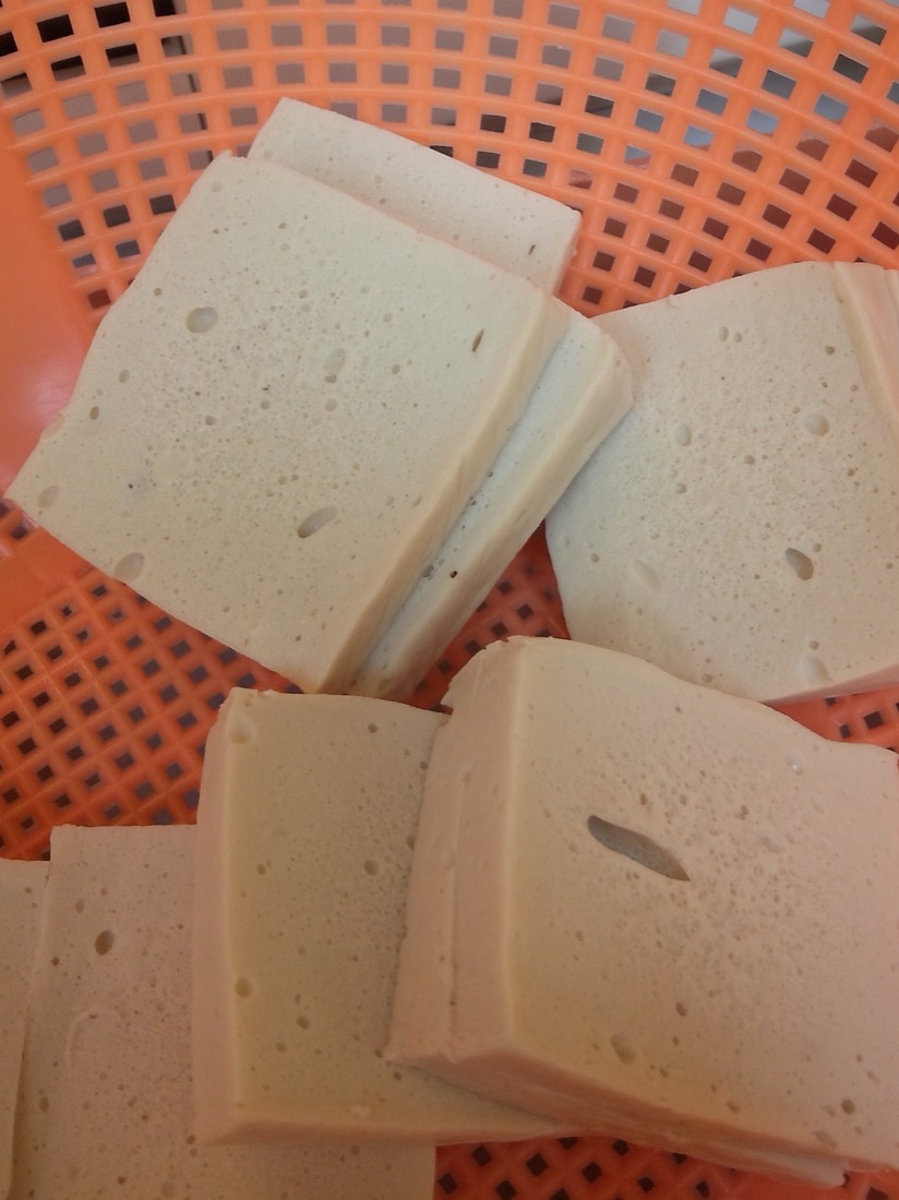 White square blocks of baiye tofu with a fine pored interior, in an orange colander