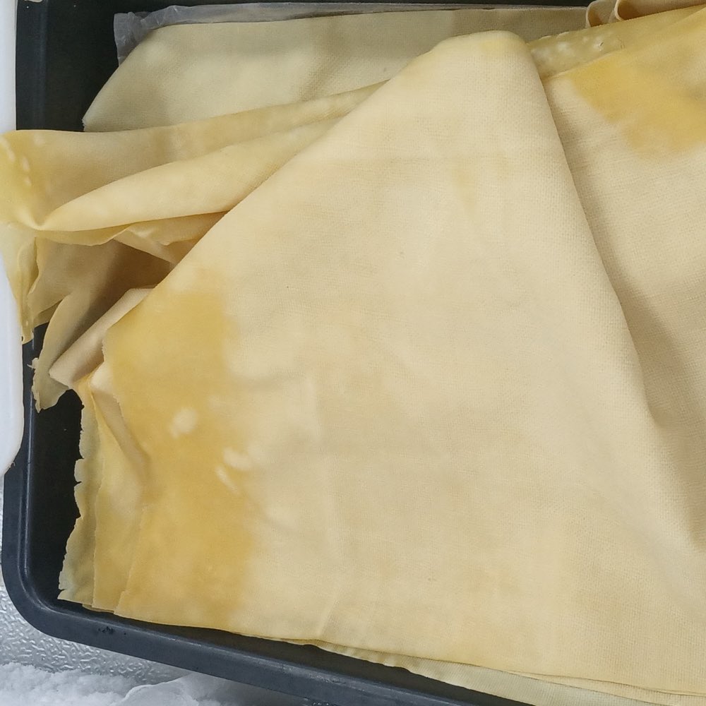 Thin pale-yellow bean-curd sheets unfolded in a tray