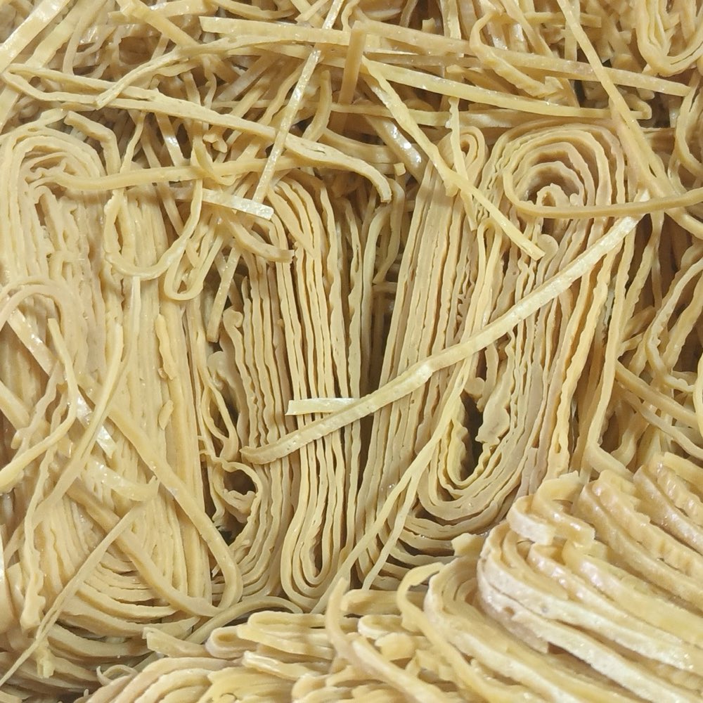 A close-up pile of pale dried-tofu shreds that resemble noodles