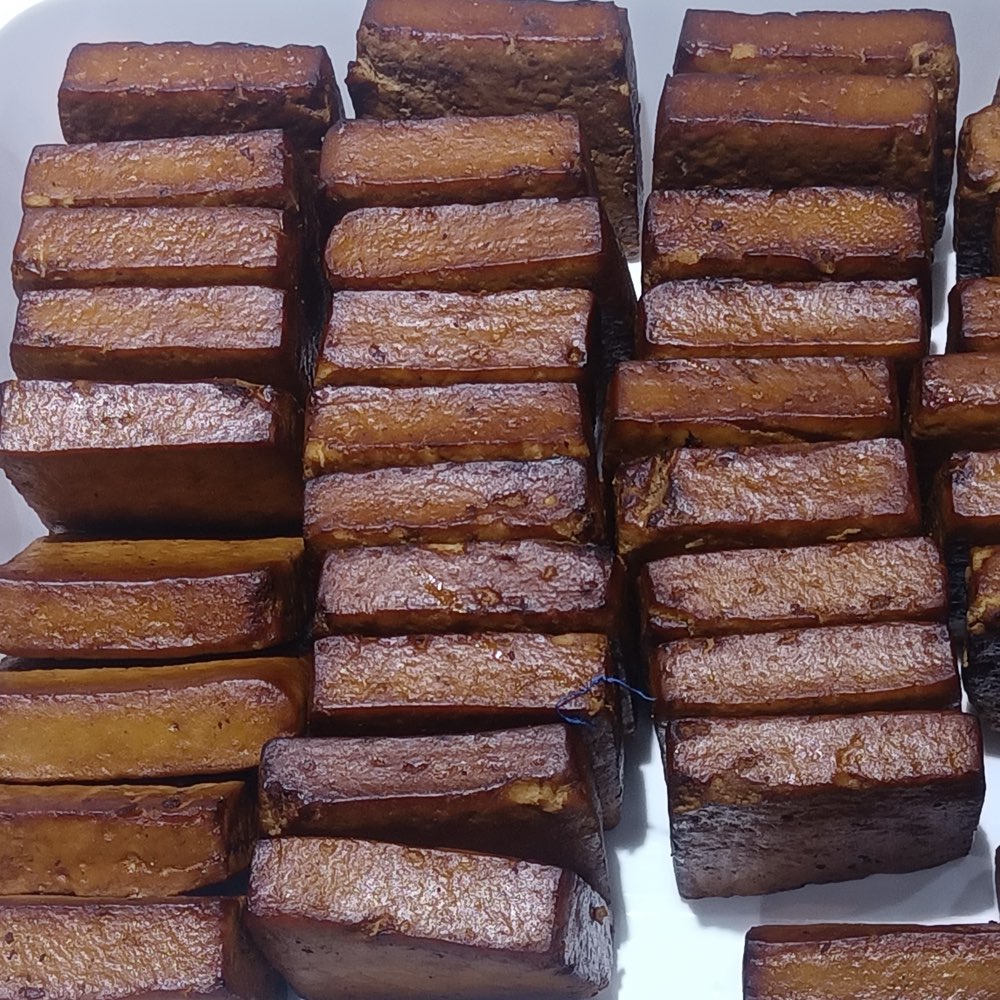 Stacked blocks of dark soy-braised brown pressed dried tofu, the cut faces showing a paler interior